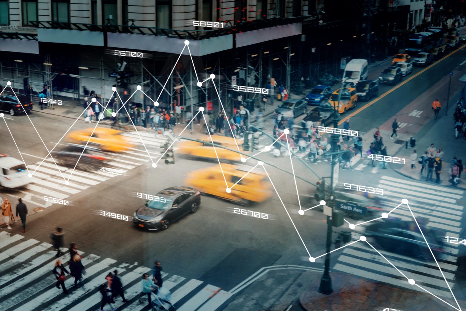 A bustling city street with pedestrians crossing at a crosswalk.